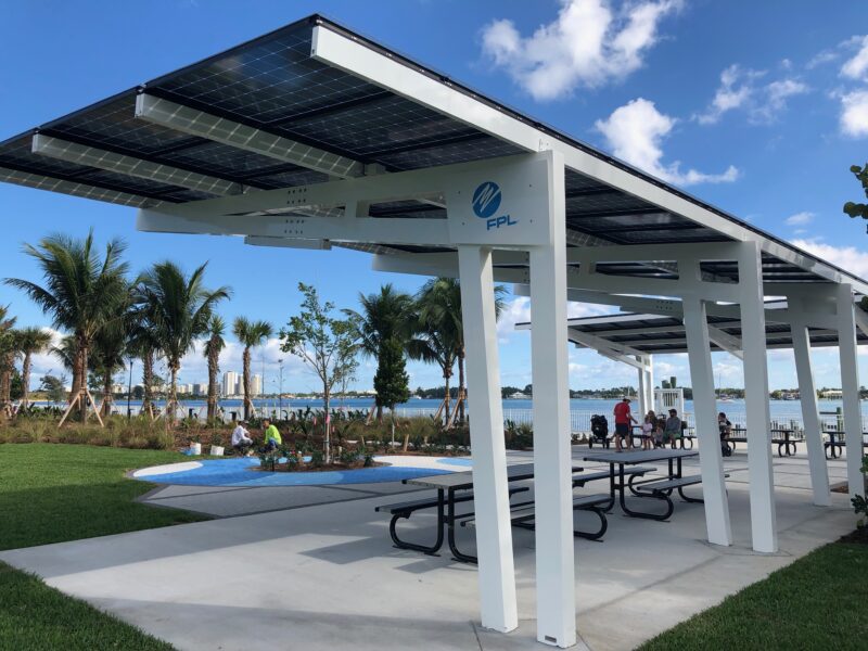 Solar Panel Canopy Shade Structure provides shade and solar power for people sitting on benches in front of the water at the Manatee Viewing Center in Florida