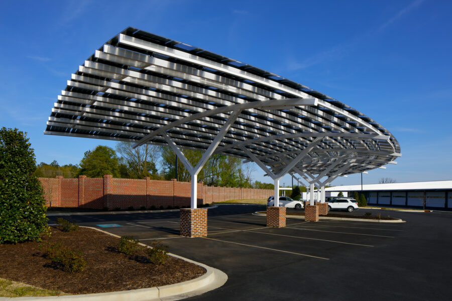 Solar Carport with Custom LSX Solar panels built over parking lot surrounded by grass with two cars parked at Marlboro Electric in South Carolina