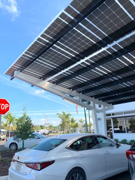 SolarScape Solar Carport with view of LSX Module Panels covering parking spaces with cars parked underneath in front of a white office building