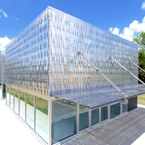 Overall Top View of University of Kansas Engineering Research and Teaching Facility with glass solar awning covering the entrance to create shade in vibrant Kansas landscape setting.