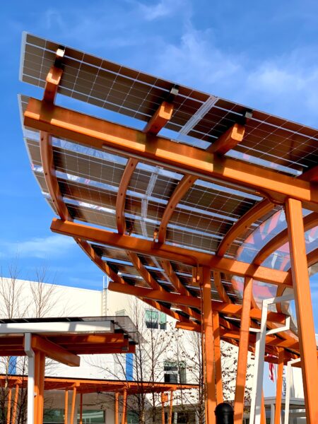 Custom LSX Curved Canopy structures providing shade and solar power in front of K-12 school.