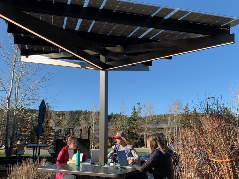 Solar Charging Table provides shade, comfortable seating, charging and lighting for people sitting at this outdoor space.