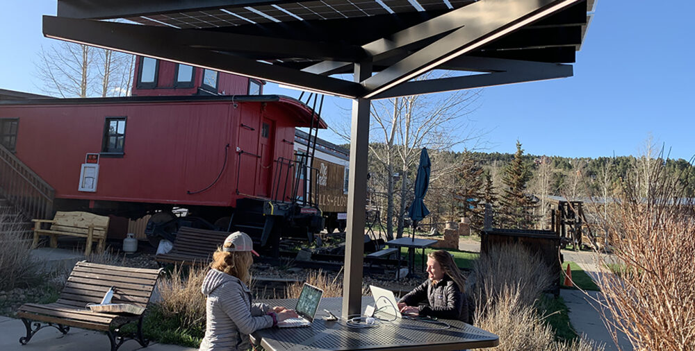 Solar Charging Table provides shade, comfortable seating, charging and lighting for people sitting at this outdoor space.